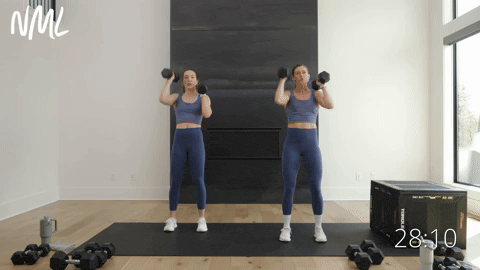two women performing an alternating single arm neutral grip dumbbell press in a back and shoulder workout