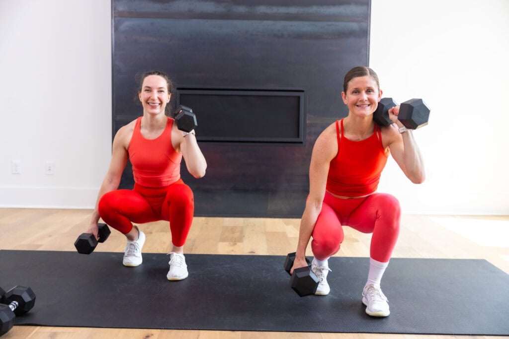 two women performing an uneven squat and hammer curl in a muscle building workout