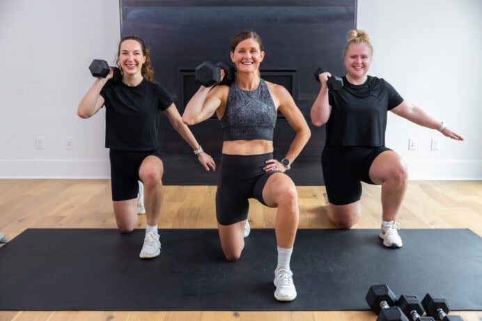 three women performing kneeling shoulder press as part of home dumbbell workout