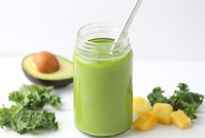 Green smoothie made with kale and pineapple in a glass mason jar with straw