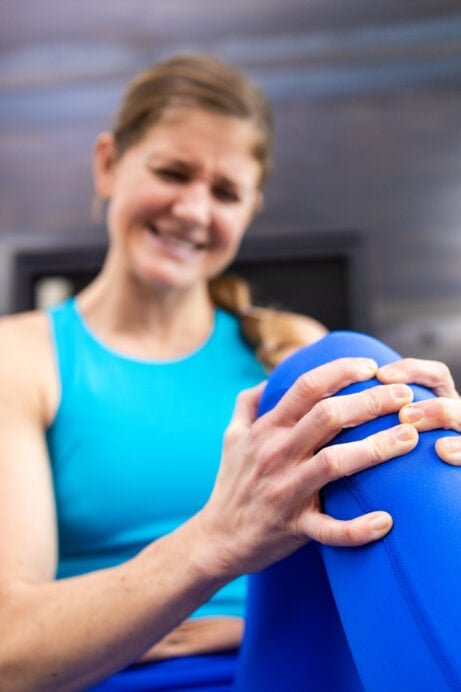 Women holding her knee due to knee pain. lunge and squat alternatives.
