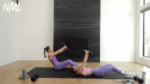 two women performing a sit up and dumbbell chop as example of core circuit exercise 
