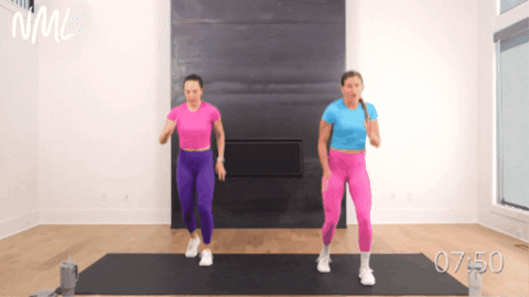 standing women performing ski runs with a lateral lunge as part of beginner cardio workout